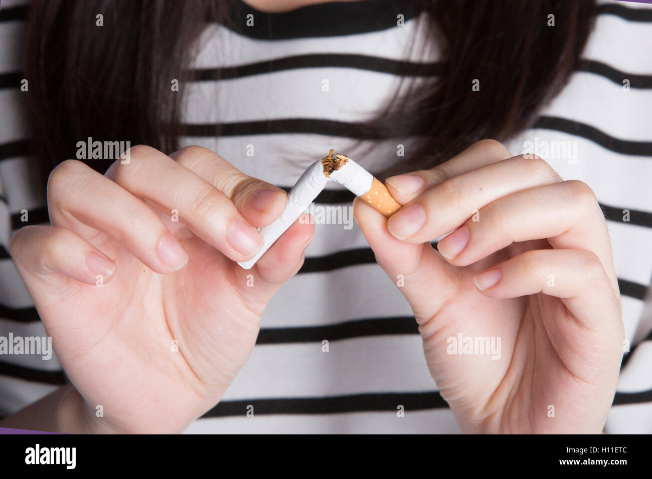 No more smoking, closeup of girl in striped clothes breaking cigarette