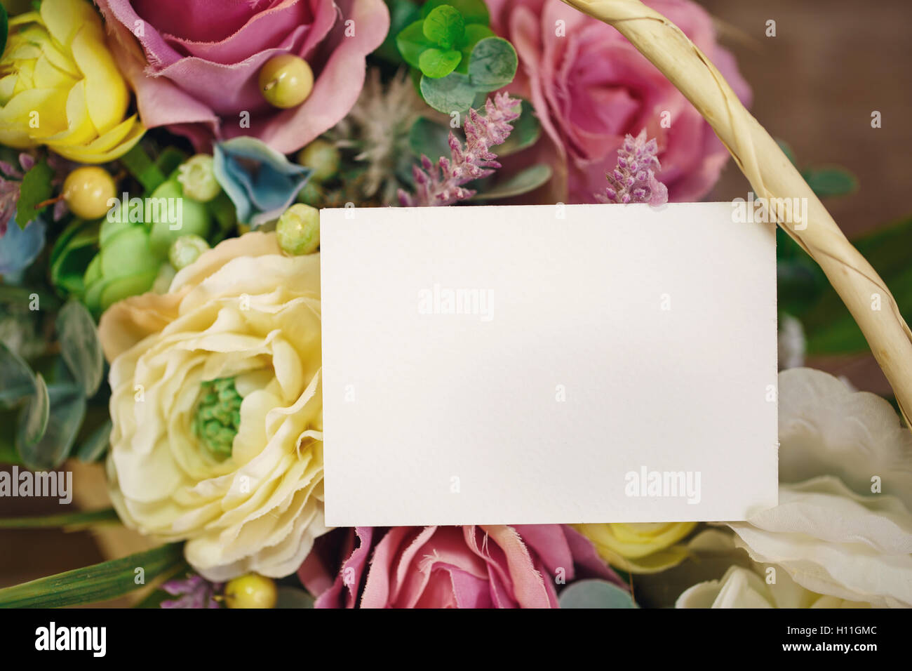 flowers in basket on the light wooden background. Space for text. Stock Photo