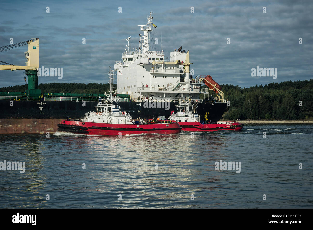 Two tugs guide a grain tanker along the Curonian Lagoon Stock Photo