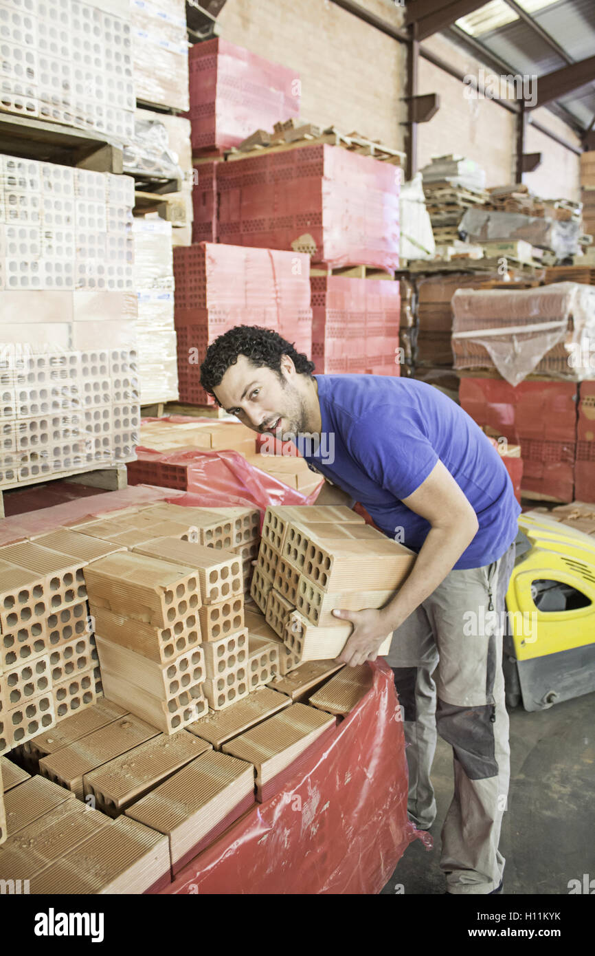 Shop worker carrying bricks, construction Stock Photo