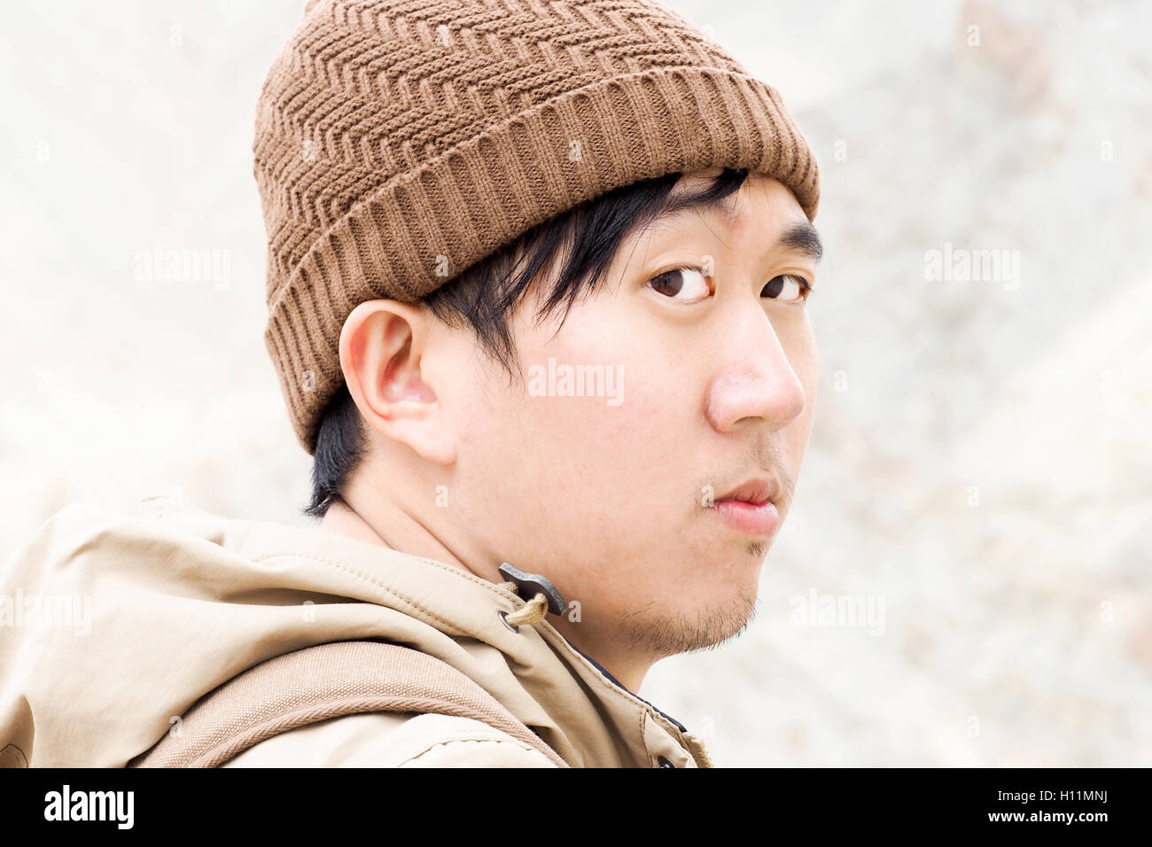 Close-up of Asian male traveler wearing beanie and rainy coat in