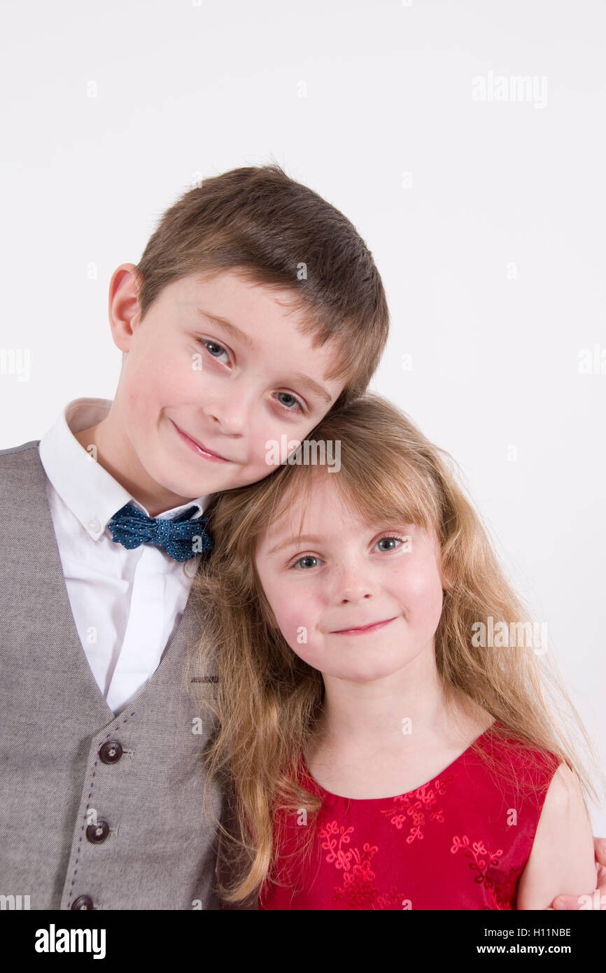 Siblings : 7 year old boy & younger sister aged 6 wearing formal evening dress, studio portrait isolated on white Stock Photo