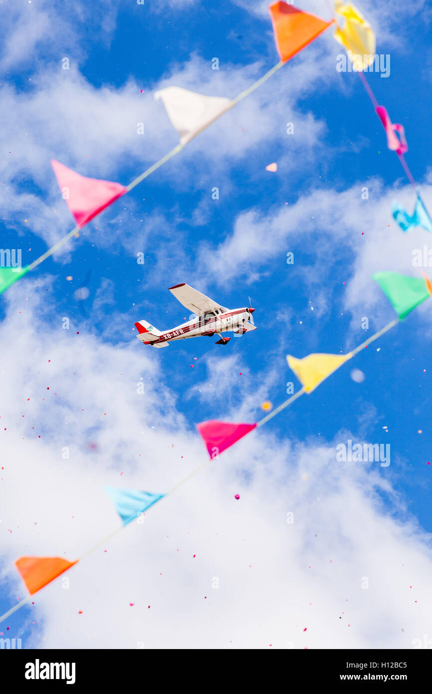 A plane releasing confetti while flying in bright and cloudy day Stock Photo