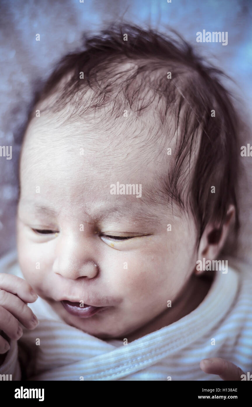 new born baby curled up sleeping on a blanket, multiple expressi Stock