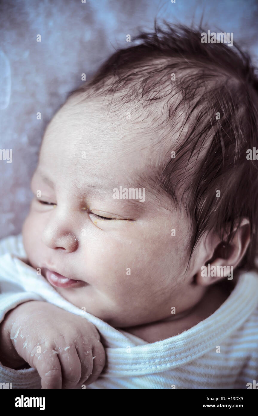 new born baby curled up sleeping on a blanket, multiple expressi Stock