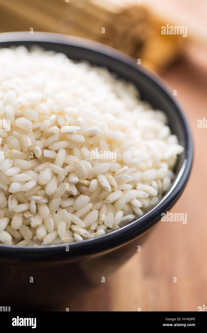 Arborio rice in bowl on wooden table. Stock Photo