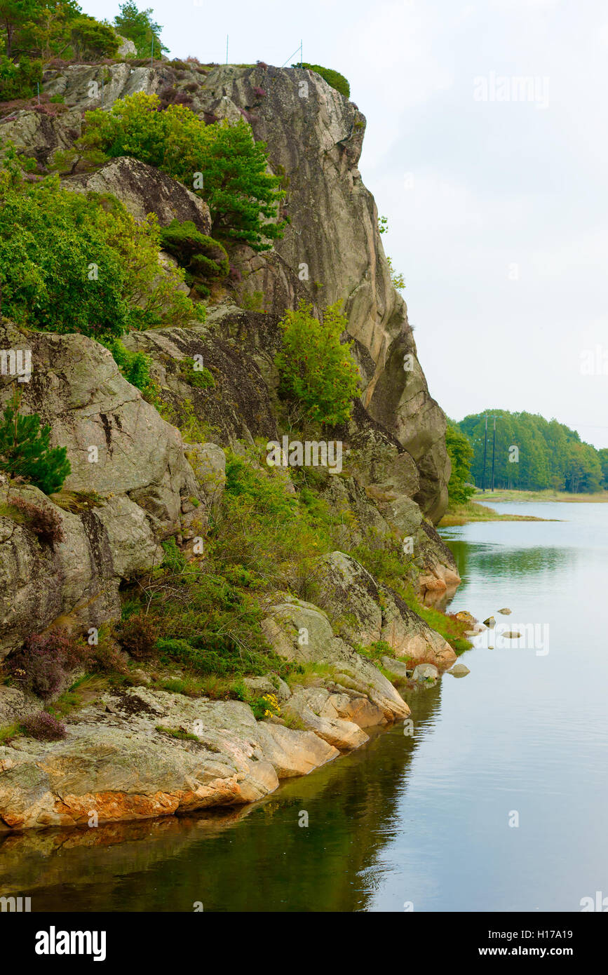 Steep cliff side with windless river below on a misty day in early fall. Sundsby on the Swedish west coast. Stock Photo