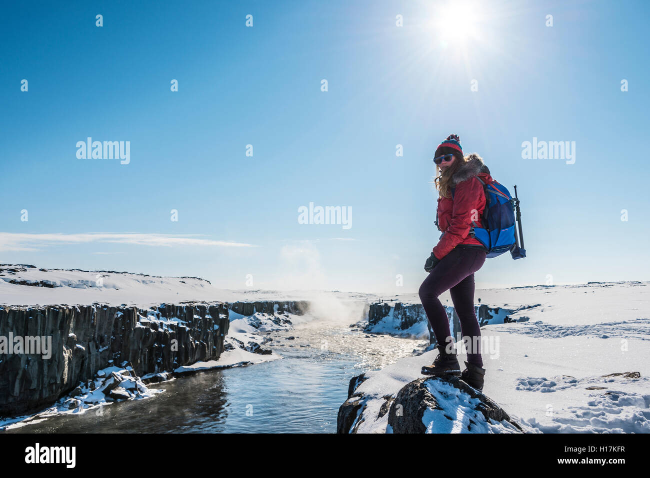 Woman looking into camera, Hafragilsfoss Waterfall in winter, Northeastern Region, Iceland Stock Photo