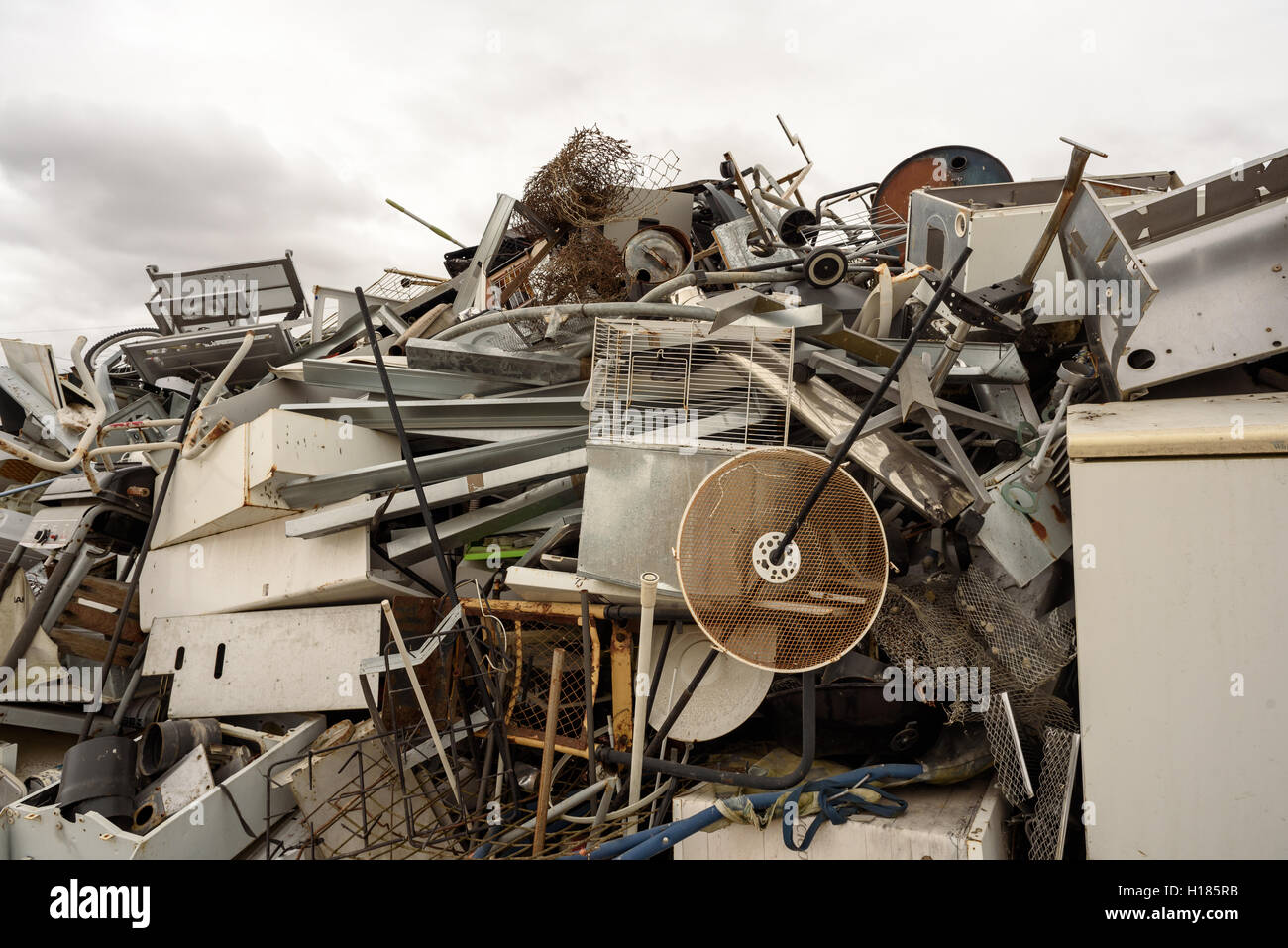 Broken pile of scrap metal and broken household white goods at a recycling dump with an overcast depressing sky Stock Photo