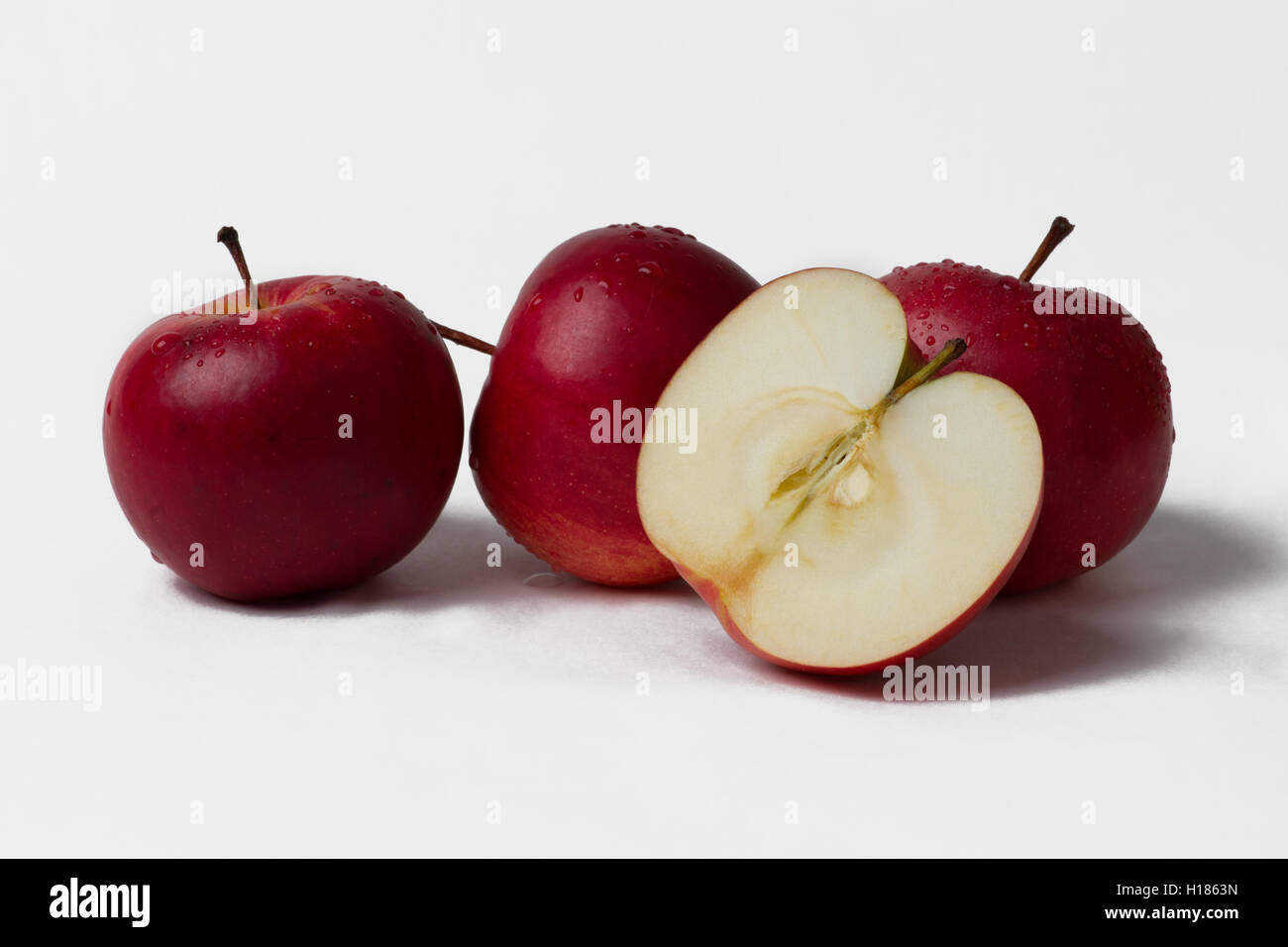 Three and a half red apple fruits isolated against white background. Healthy vitamin food. Stock Photo
