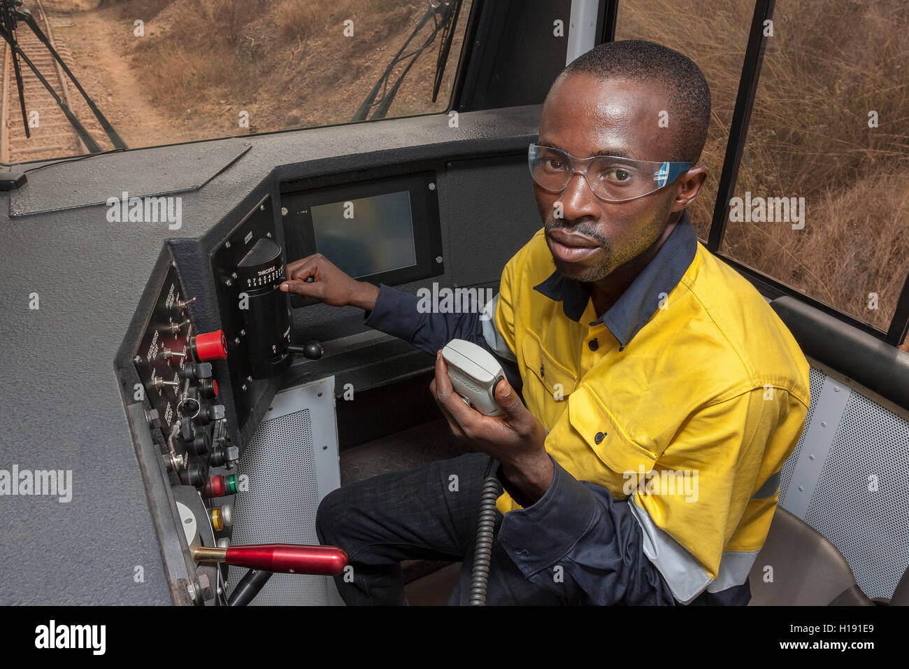 Port operations for managing and transporting iron ore. Local national and train driver on trunk radio to train control in cab of Grindrod locomotive. Stock Photo