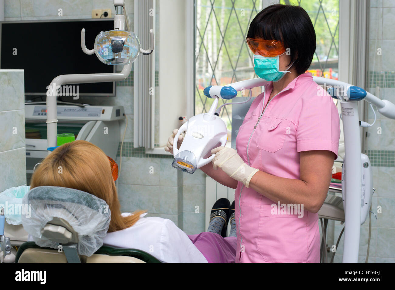 Female dentist examining patients teeth in the dentists chair Stock Photo