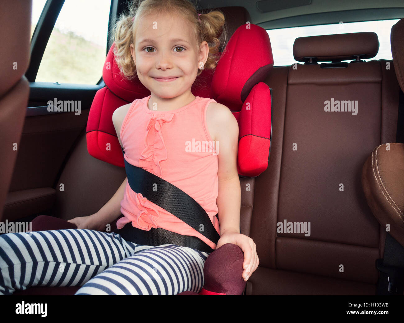 Portrait of happy little child girl sitting comfortable in car seat