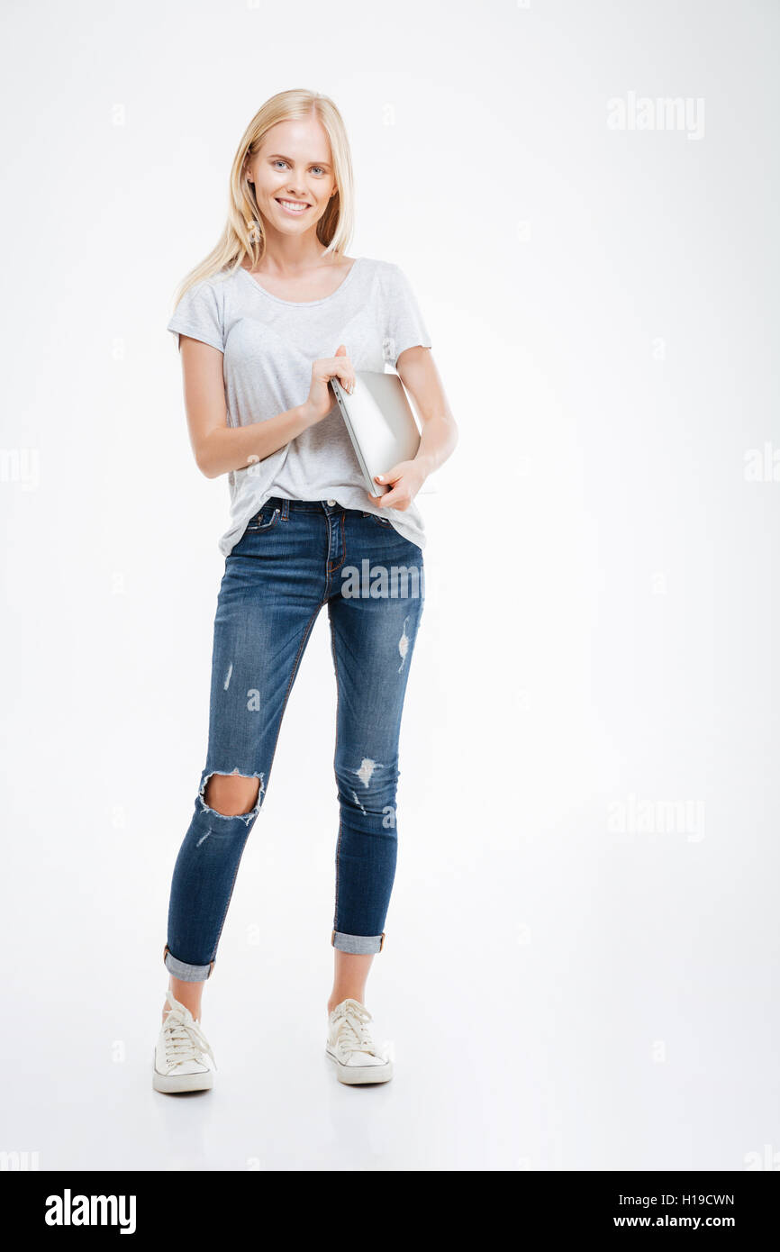 Full length portrait of a happy casual woman standing with laptop ...