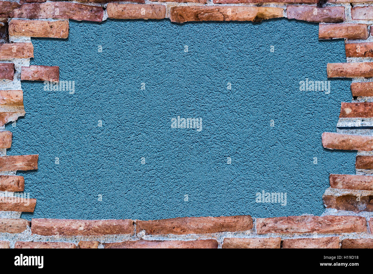 Ancient red brick wall with a hole over a bakground blue. Stock Photo