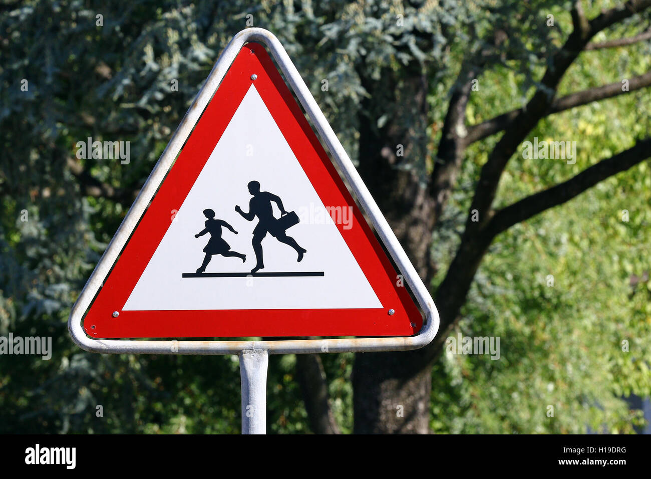 White and red triangle warning school sign with students running and a nature background Stock Photo
