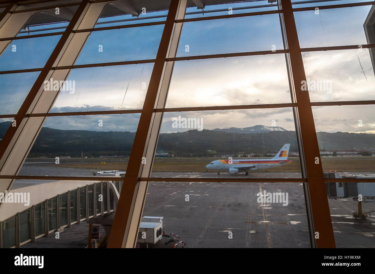 Iberia aircraft taxis at Bilbao Airport, Spain. Sot through window of terminal building Stock Photo