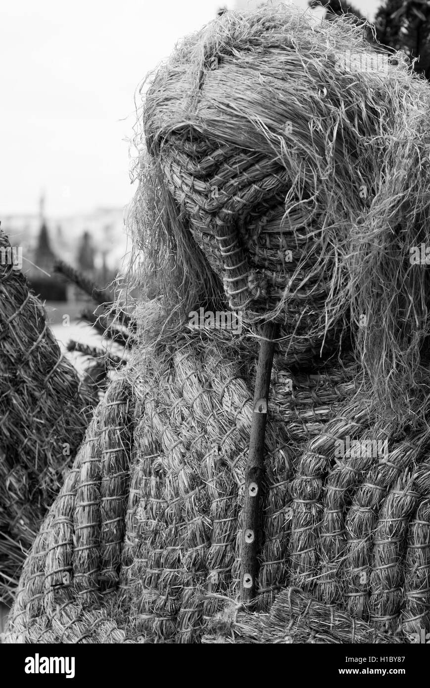 black and white photo of a straw angel playing a wooden flute Stock Photo