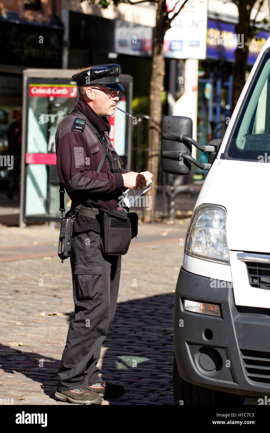 Dundee City Council traffic warden issuing a parking ticket to a parked delivery van along the High Street in Dundee, UK Stock Photo