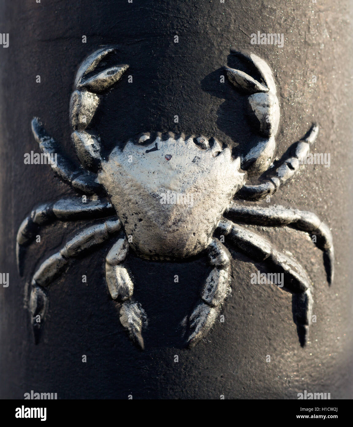 Pattern crab on a cast iron post in the light of the sun. Close-up. Stock Photo