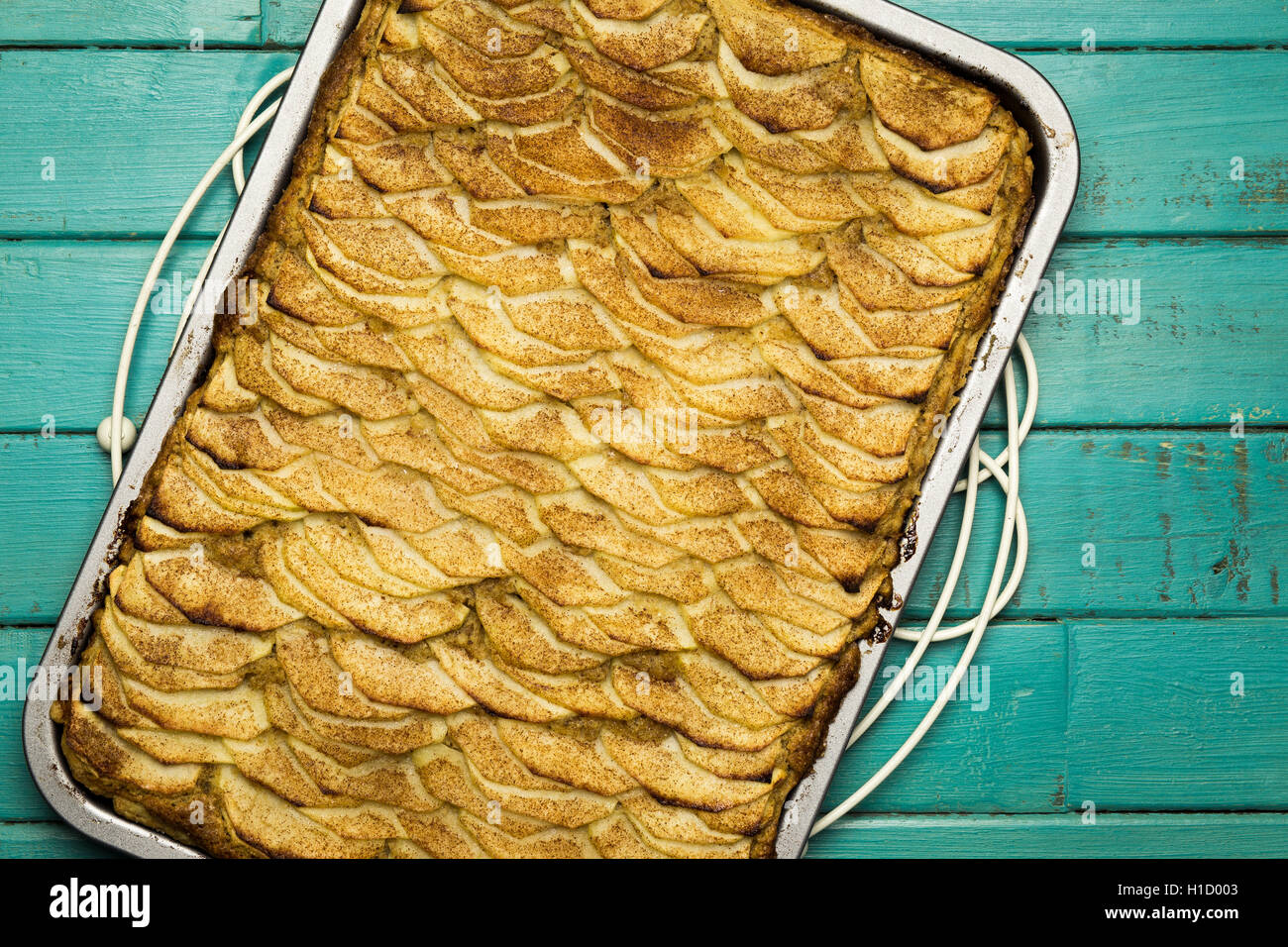 Apple cinnamon tart with hazelnut frangipane in baking tray on turquoise background Stock Photo