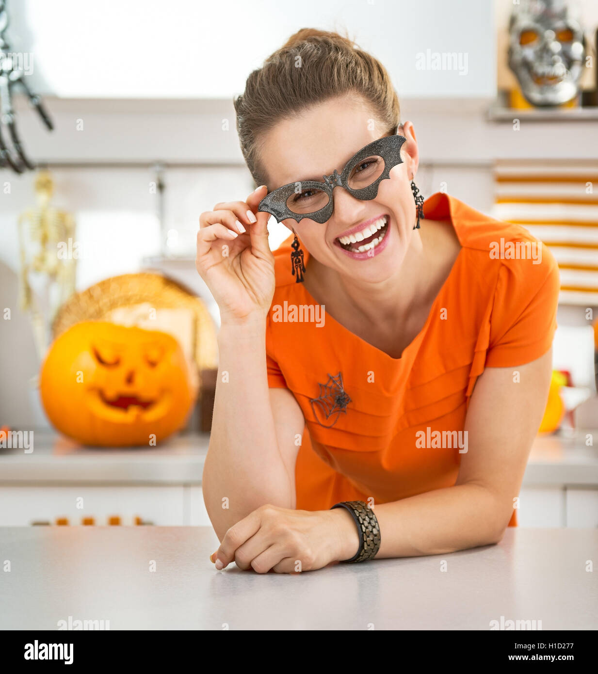 Frightful Treats all the way. Portrait of smiling young woman in party bat glasses in the Halloween decorated kitchen Stock Photo