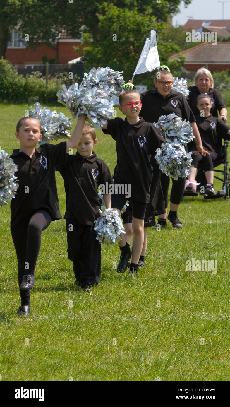 Teenage and children cheerleaders in black with silver pompoms Stock Photo
