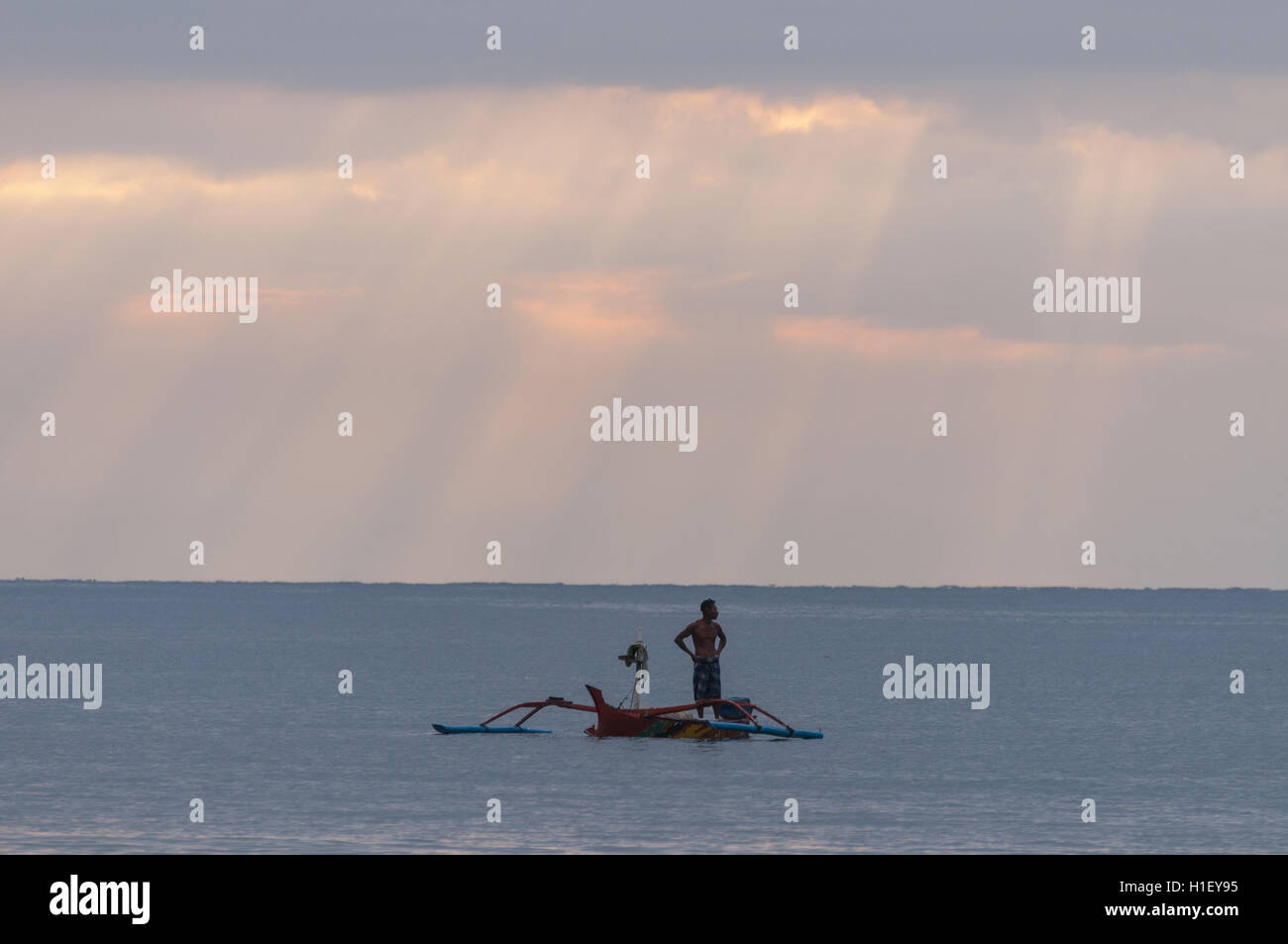 Indonesia, Bali, Kalibukbuk, cloudy ocean sunset with outrigger canoe Stock Photo