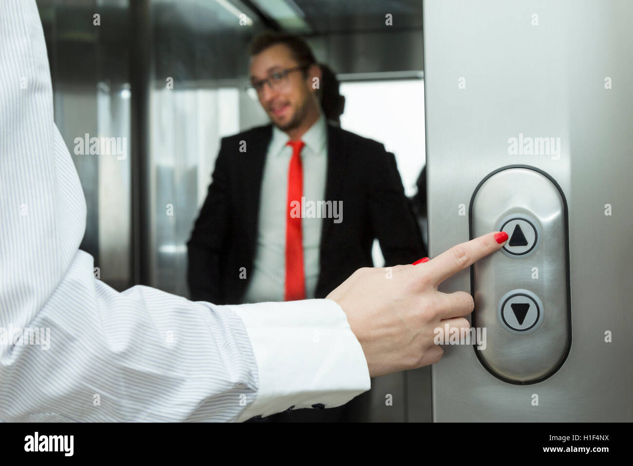 Female hand pressing elevator up button. Businessman inside of the