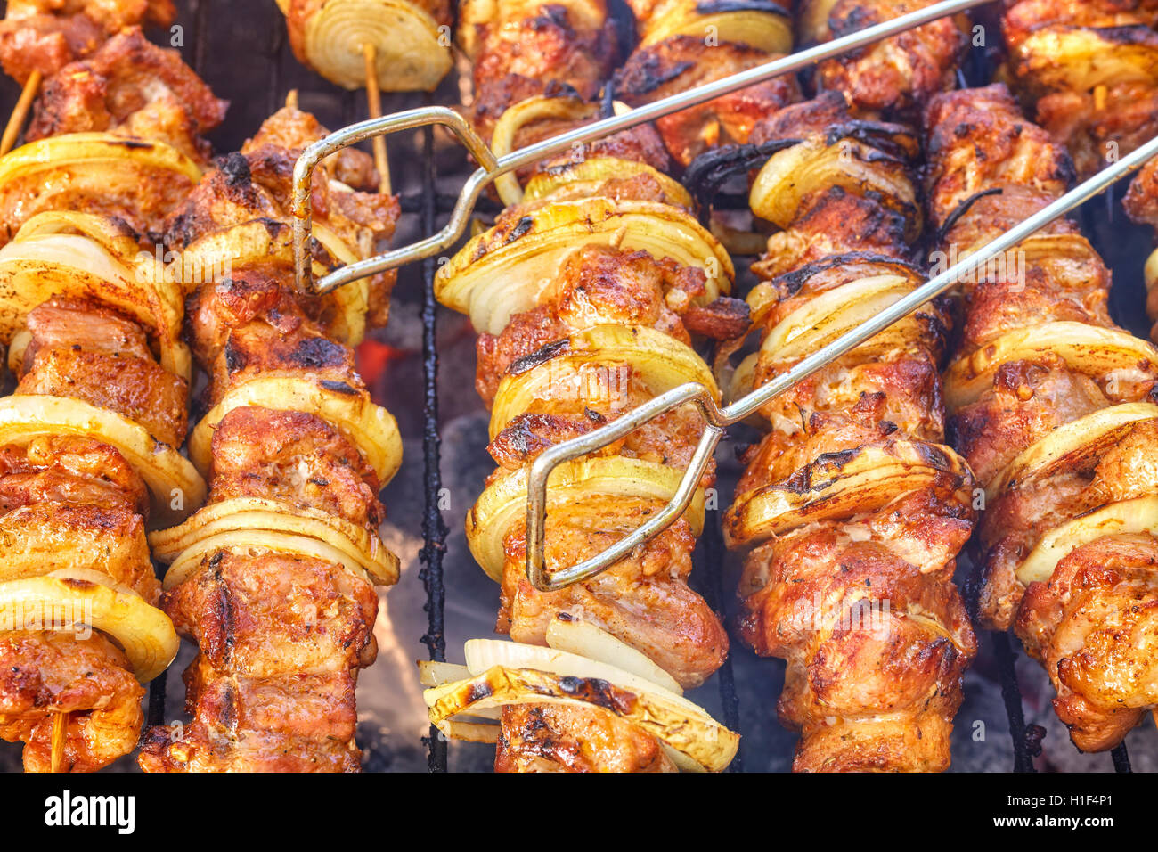 Close up picture of barbeque tongs on meat skewers with onions, selective focus. Stock Photo