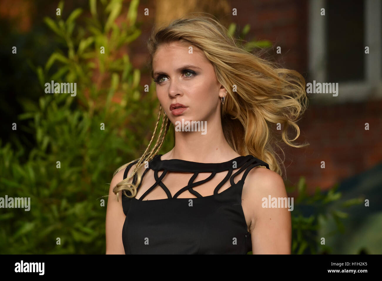 Portrait of blond teenager dressed up in black dress looking away, with the wind blowing on her hair Stock Photo