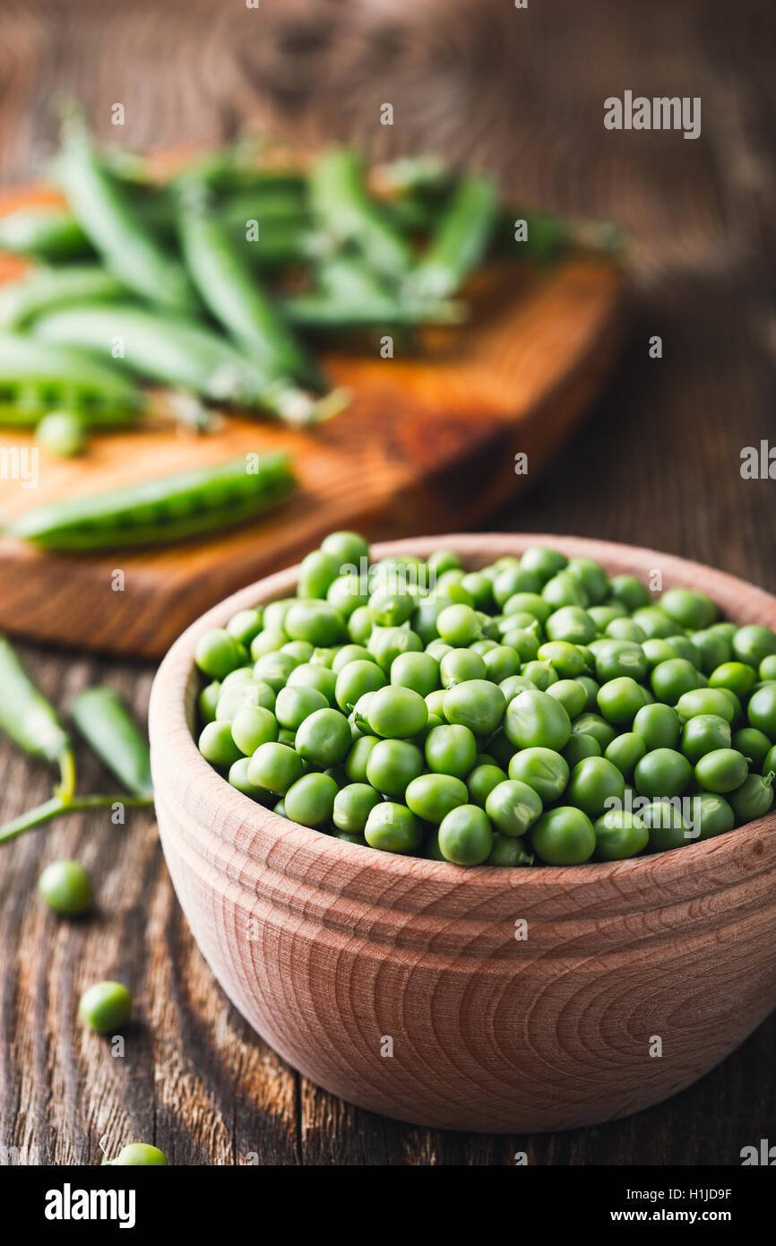 Green peas in wooden bowl on rustic background, harvest time Stock Photo
