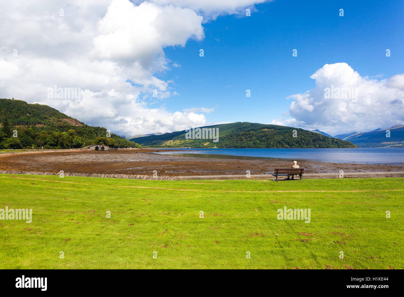 Lonely elderly man sitting on the bench and watching the lake. Stock Photo
