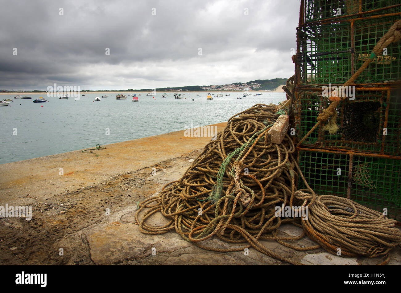 Stack of fishing traps and ropes in a pier and anchored boats on the ...
