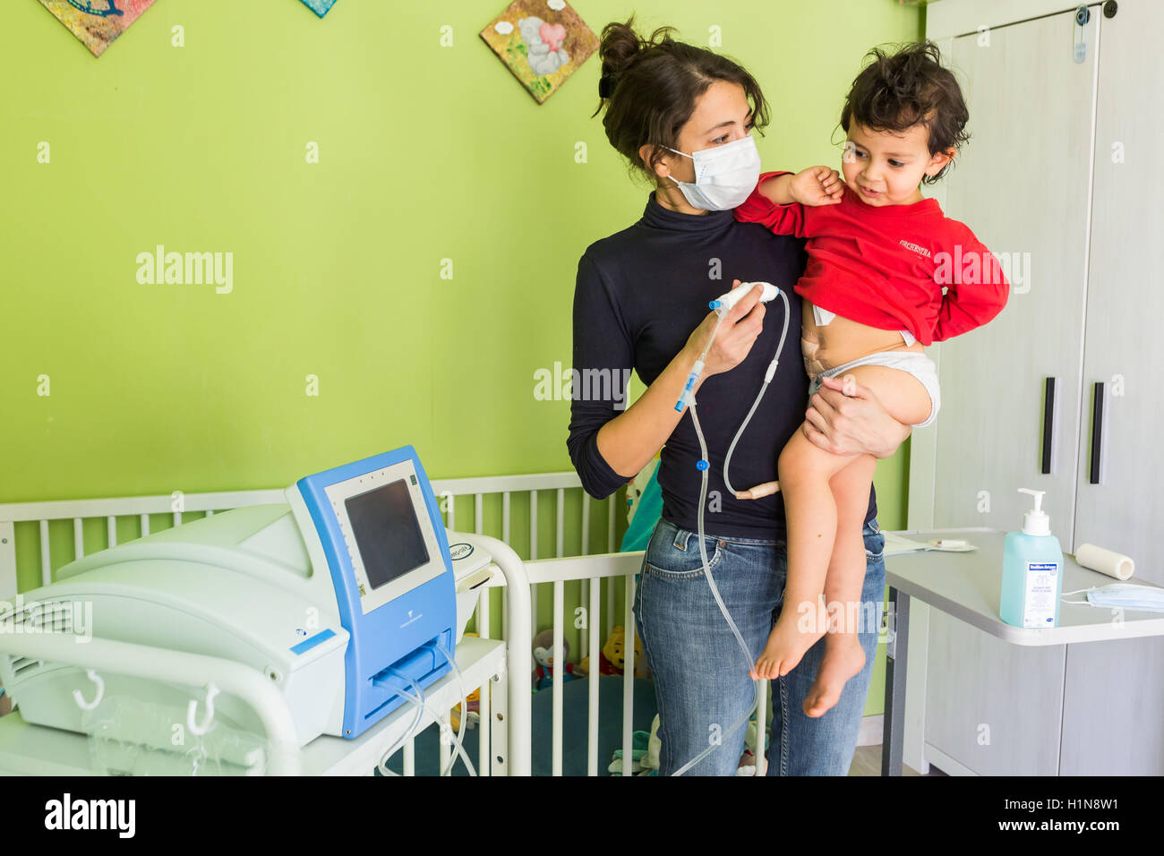 2 year-old boy suffering from kidney failure, undergoing a automated peritoneal dialysis at home. Stock Photo