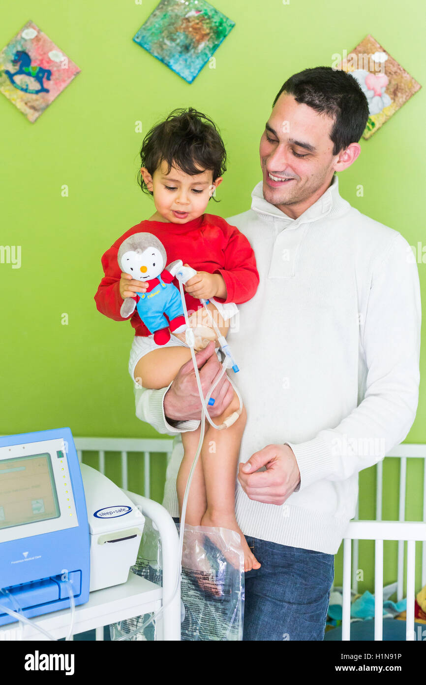 2 year-old boy suffering from kidney failure, undergoing a automated peritoneal dialysis at home. Stock Photo