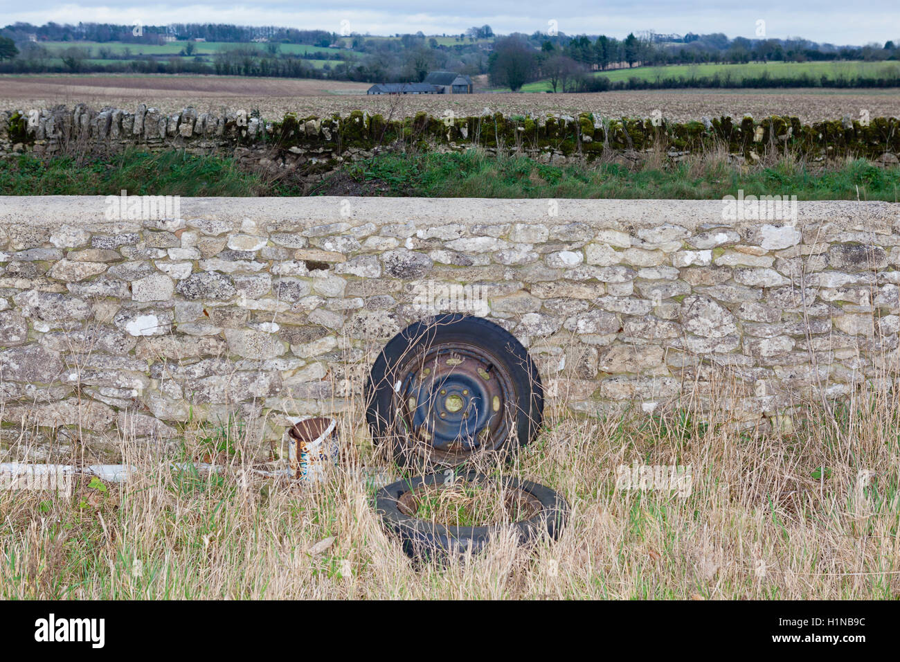 Cotswold dry stone wall, seen and unseen, with rubbish dumped out of sight behind. Stock Photo