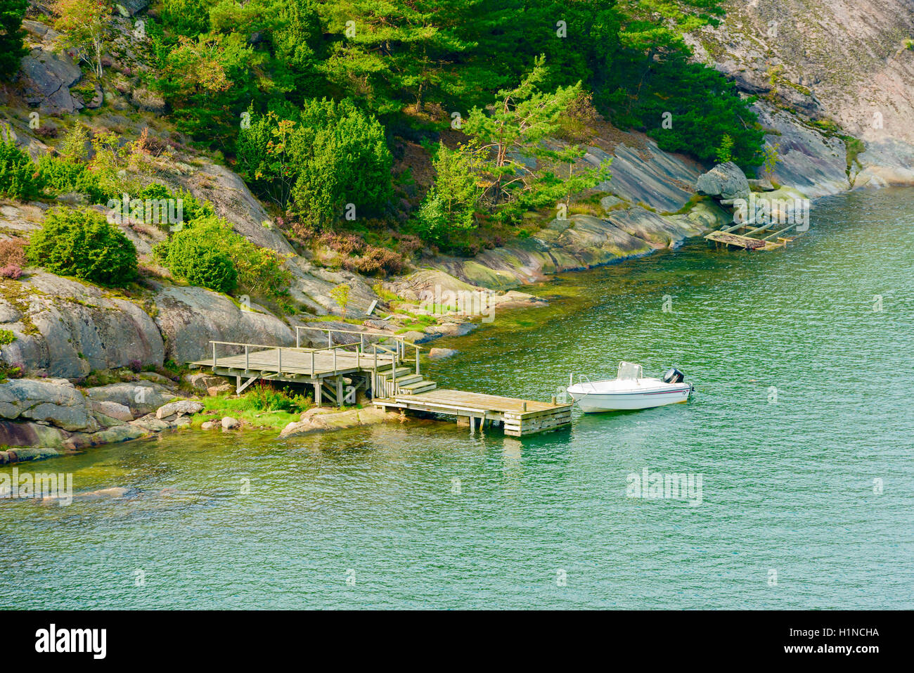 Mjorn, Sweden - September 9, 2016: Travel documentary of small motorboat moored beside a wooden pier in coastal cliff landscape. Stock Photo