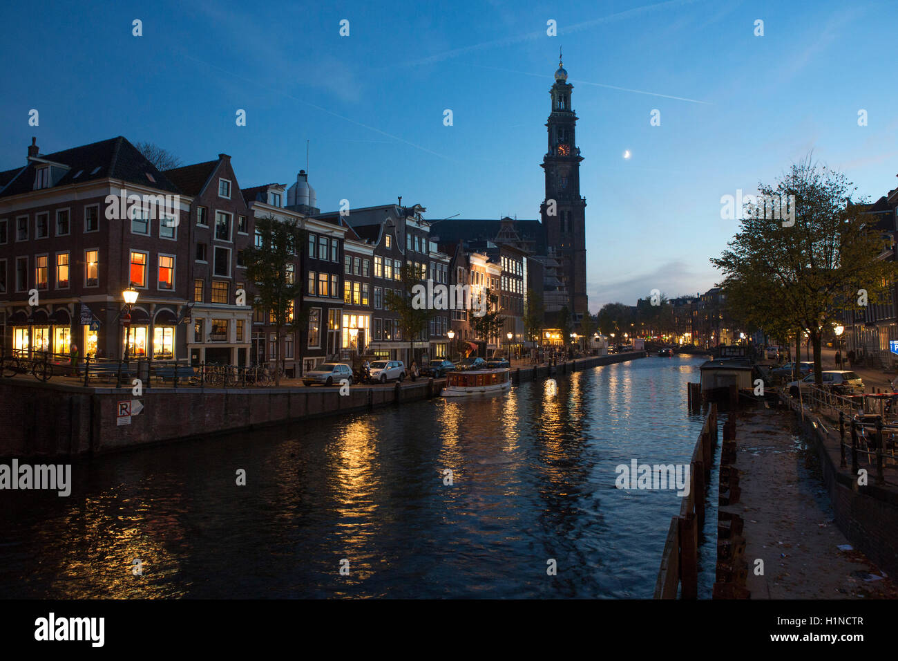 View of the Weterkerk or Wester Church at twilight on the banks of the canals in Amsterdam. Stock Photo