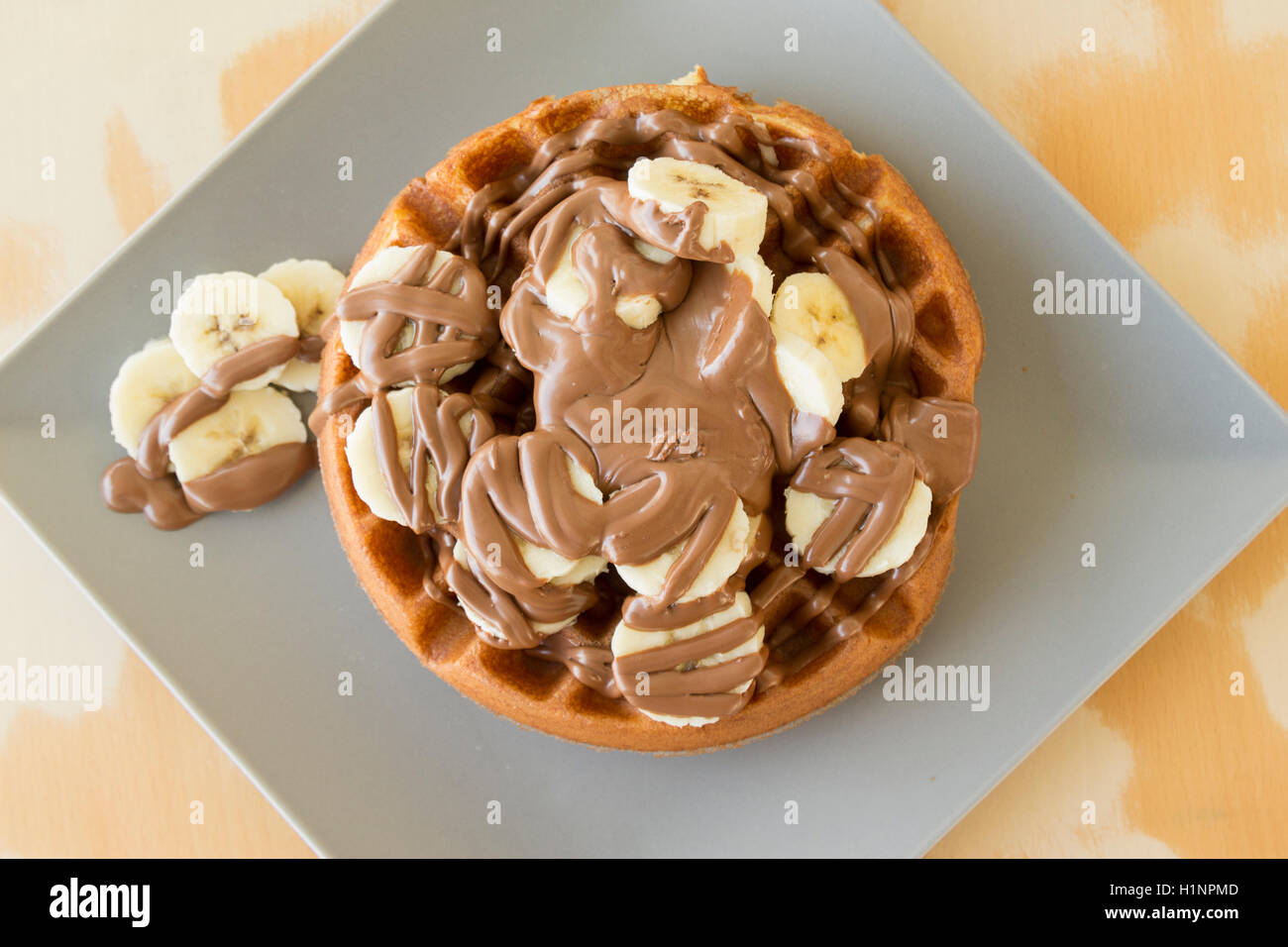 Tasty waffle with banana slices and chocolate cream on the top served ...
