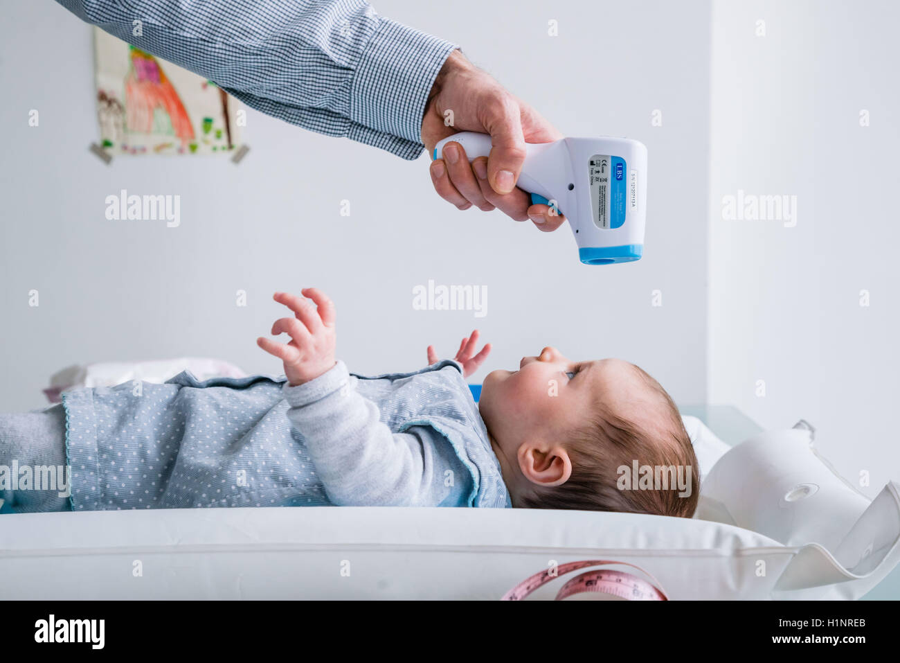 Checking the temperature of a 3 month old baby girl with forehead