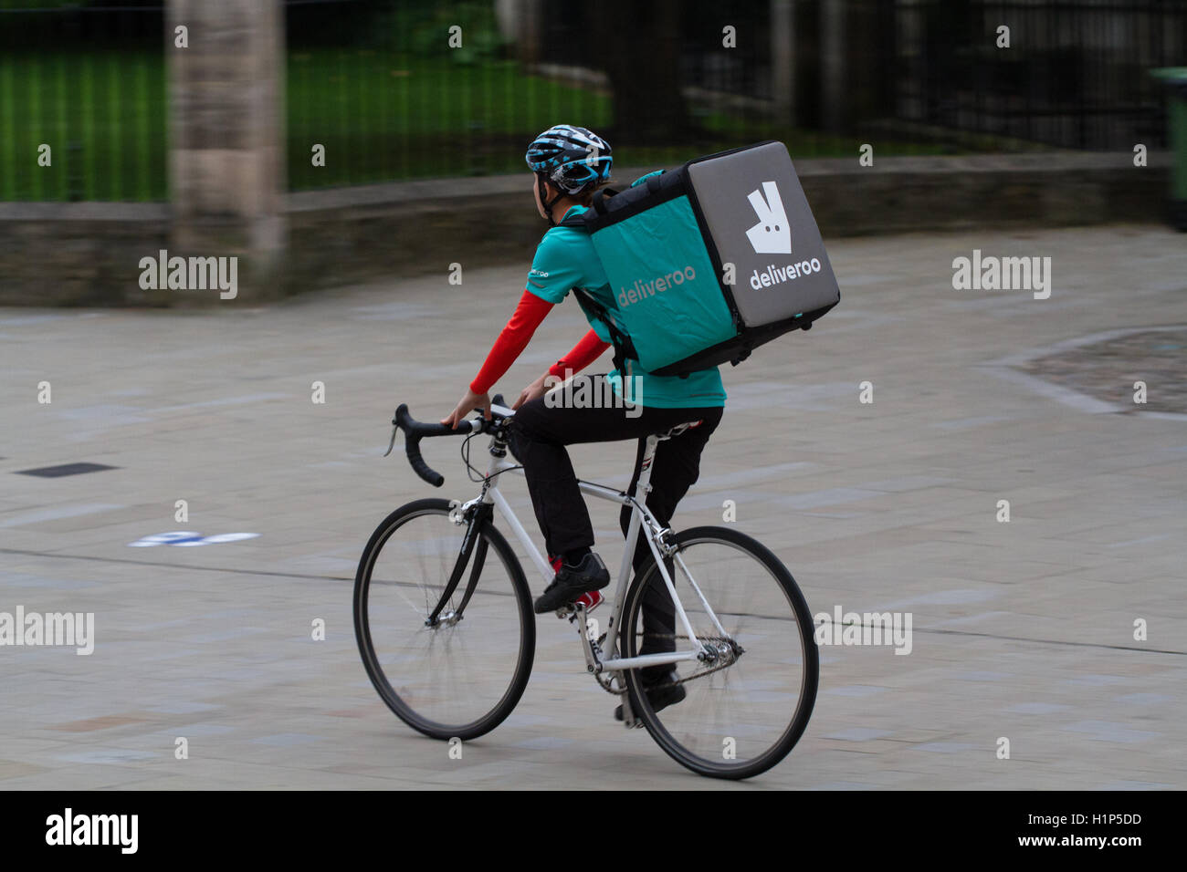 A Deliveroo cyclist from the increasingly popular hot food and fast food delivery company cycling through city streets. Stock Photo