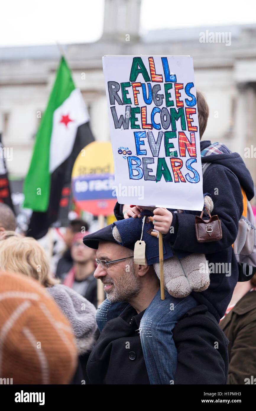 young boy on a man's shoulders waving a placard of Paddington Bear as a refugee at a pro -immigration and pro-refugee rally Stock Photo