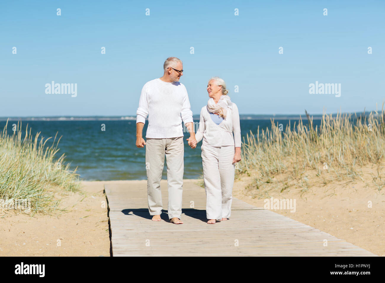 happy senior couple holding hands on summer beach Stock Photo - Alamy