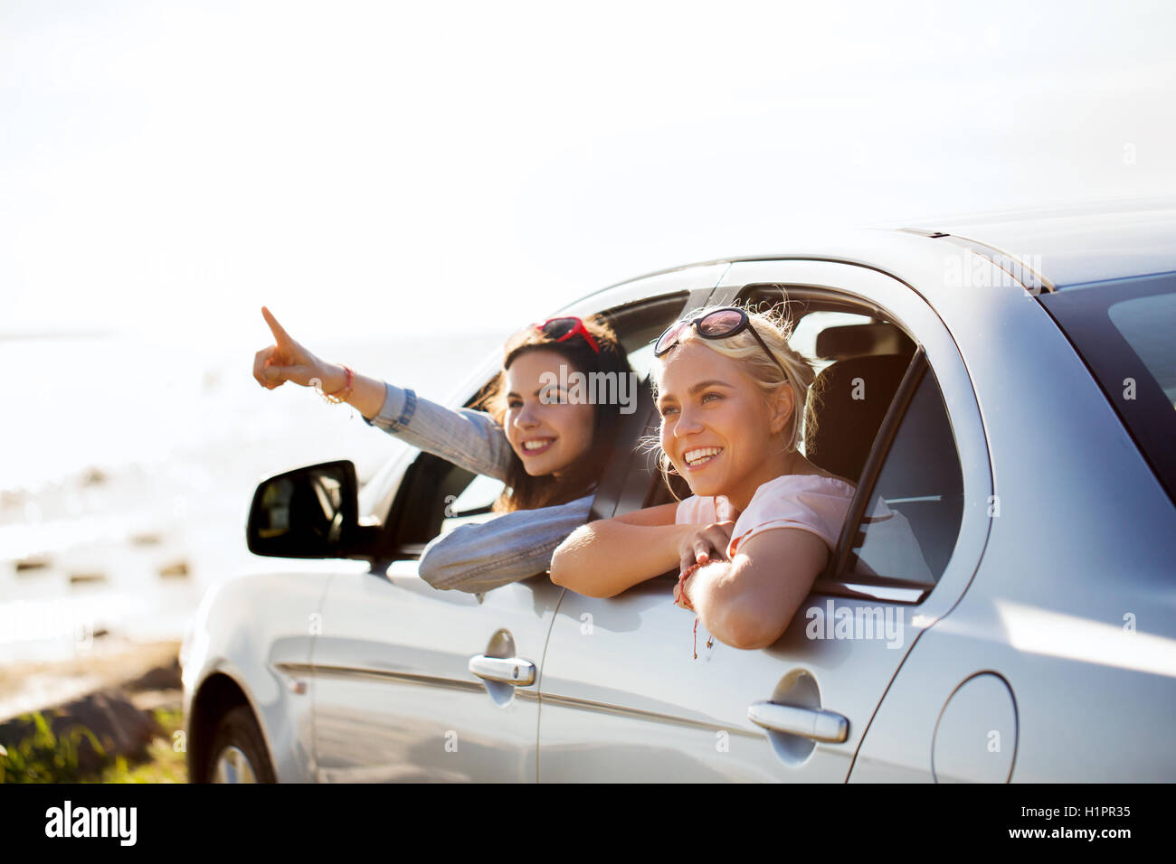 happy teenage girls or women in car at seaside Stock Photo - Alamy