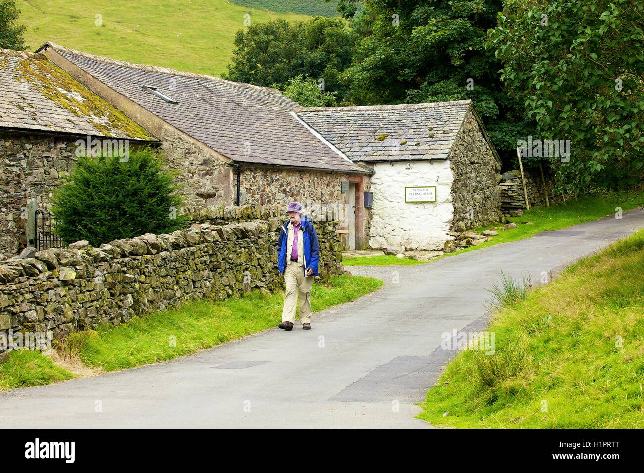 Elderly man hiking passed Mosedale Coffee Shop at the Quaker Meeting House. Mosedale, Lake District National Park, Cumbria, UK. Stock Photo