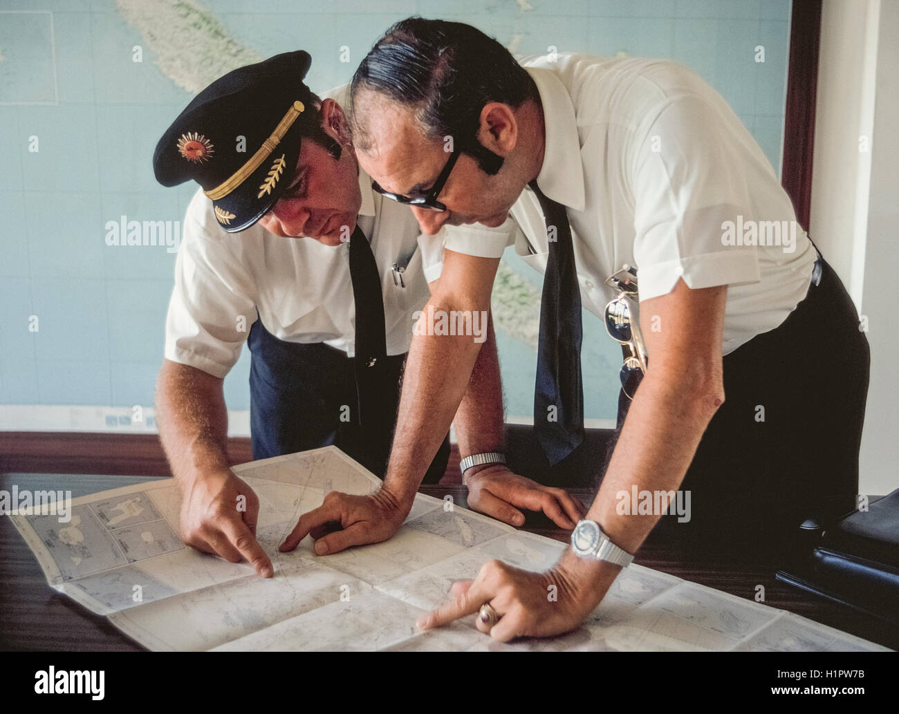 Captain Ross Zimmerman and copilot James McKenna study a map before embarking with their Convair 990 jet to fly a Modern Air Transport charter named 'Polar Bird II.' The plane carried 48 passengers via the North Pole and South Pole on a unique 32-day around-the-world tour organized by Hemphill World Air Cruises of Los Angeles, California, for the Travelers' Century Club. It was the most expensive world tour of the time (1970) at $9,760 per person. Stock Photo