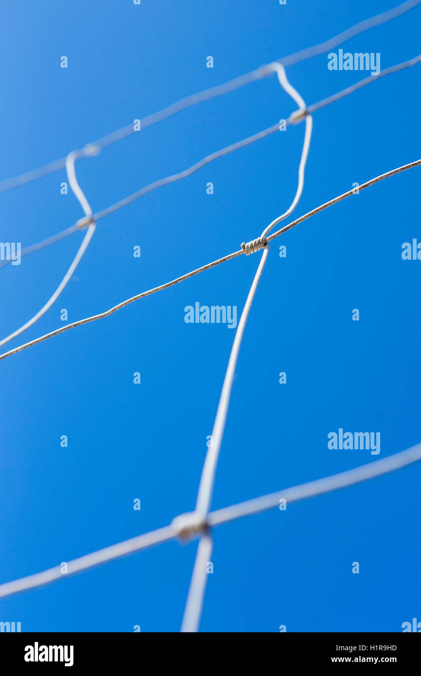 Thin twisted wire fence set aginst a deep blue sky Stock Photo Alamy