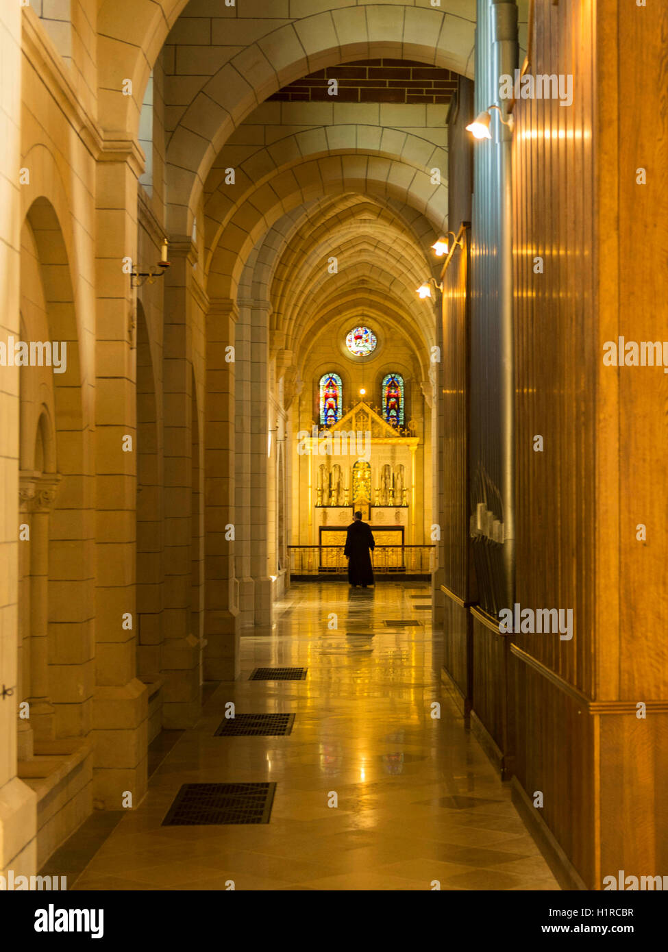 A monk takes daily stroll around the beautiful abbey framed by the stunning architecture  of the12th century Buckfast Abbey. Stock Photo