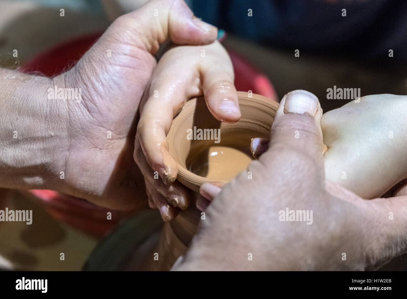 A potter guides a child's hands as the boy tries potting for the first time, Estoril, Portugal Stock Photo